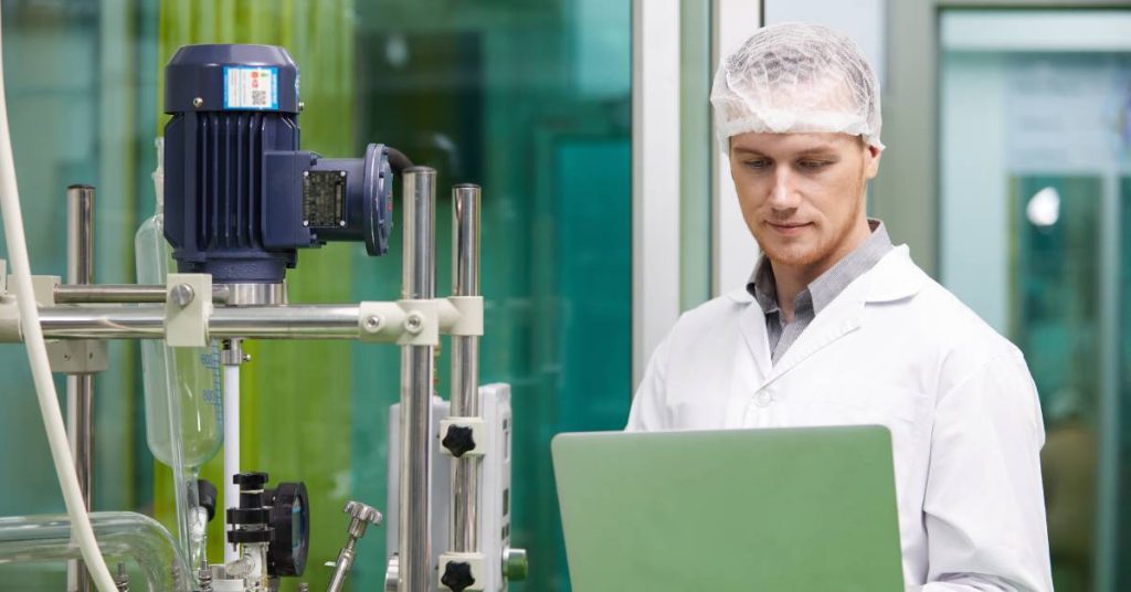 A cannabis testing laboratory technician looking over the contamination data gathered from a cannabis sample on their laptop.